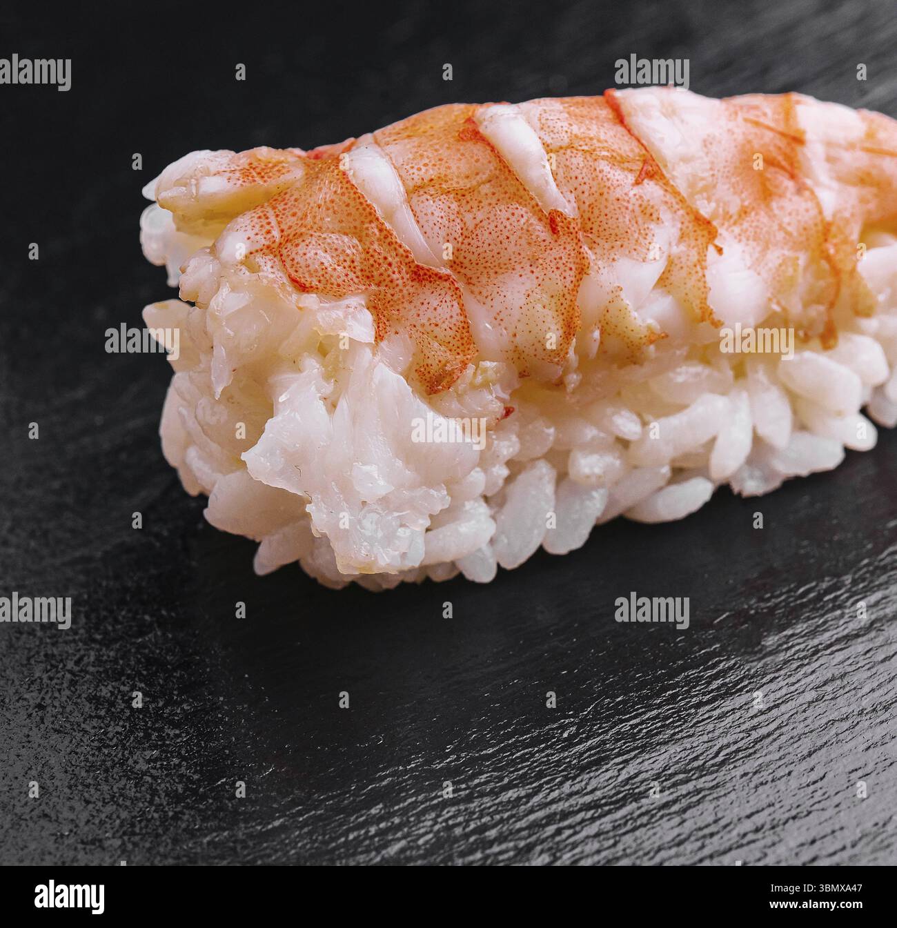 Stillleben, Sushi-Garnelen und Reis auf schwarzem Holz Stockfoto
