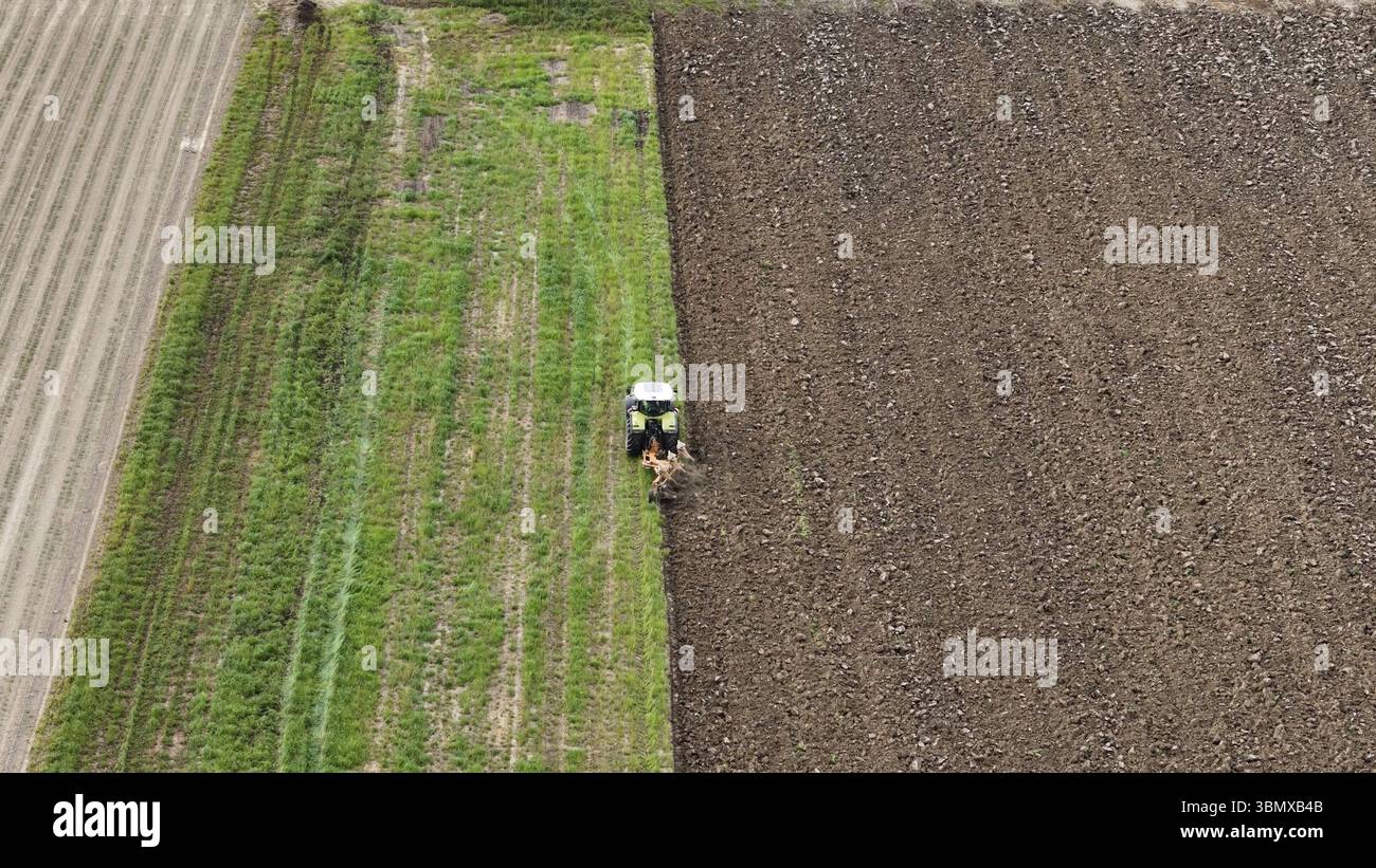 Luftaufnahme des Traktorpflügerfeldes und -Betriebs in der Landwirtschaftslandschaft als Szene des Anbaus und der Landbewirtschaftung für die Nahrungsmittelproduktion und Kultivati Stockfoto