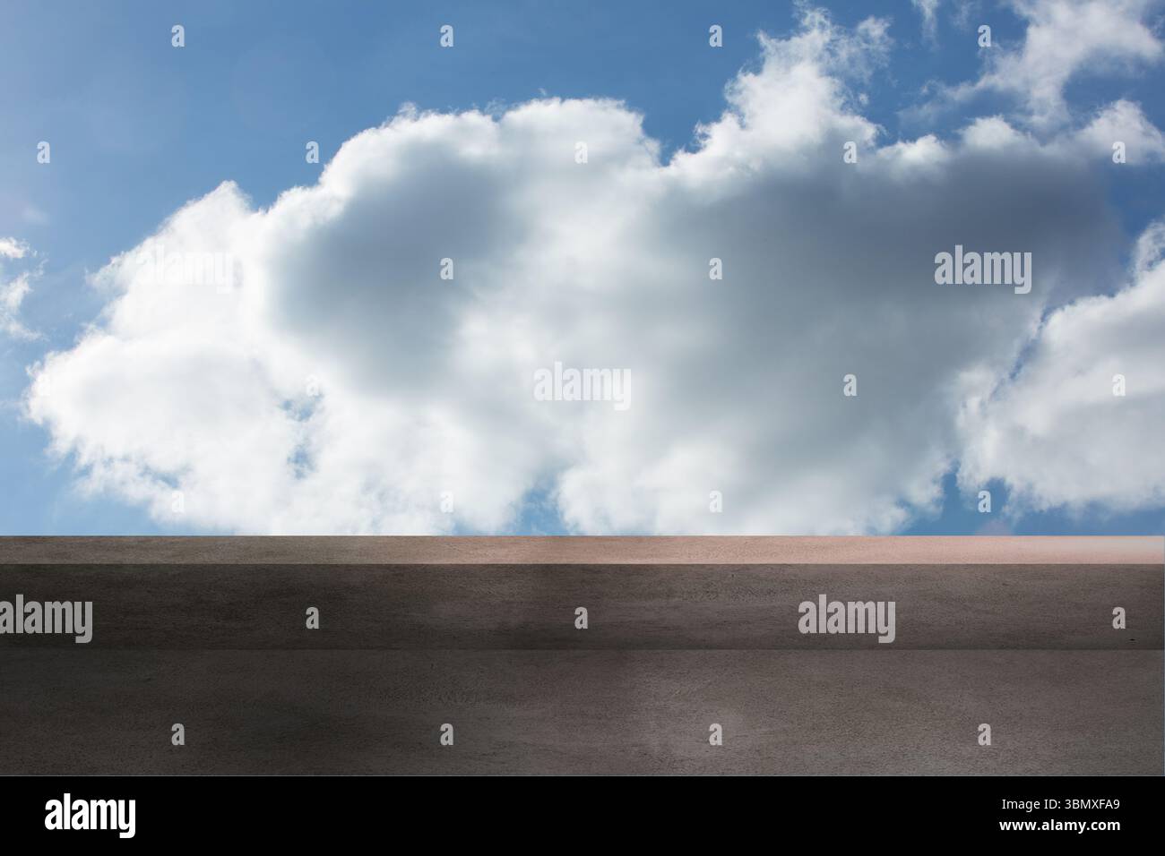 Flache zweistufige Betonplattform mit großer Kumuluswolke unter blauem Himmel Stockfoto