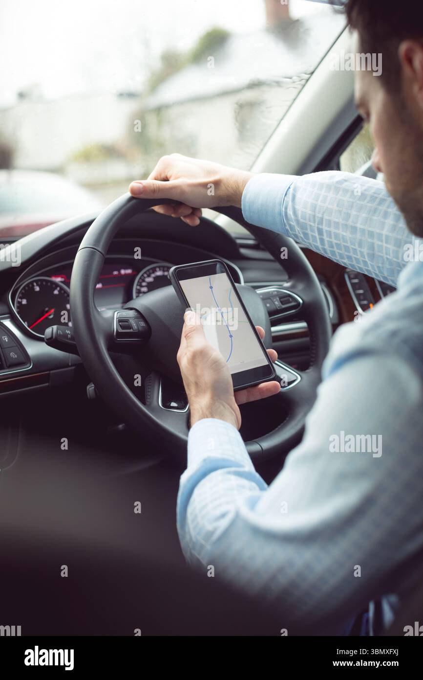 Man-fahrer mittels Smart Phone im Auto. Stockfoto