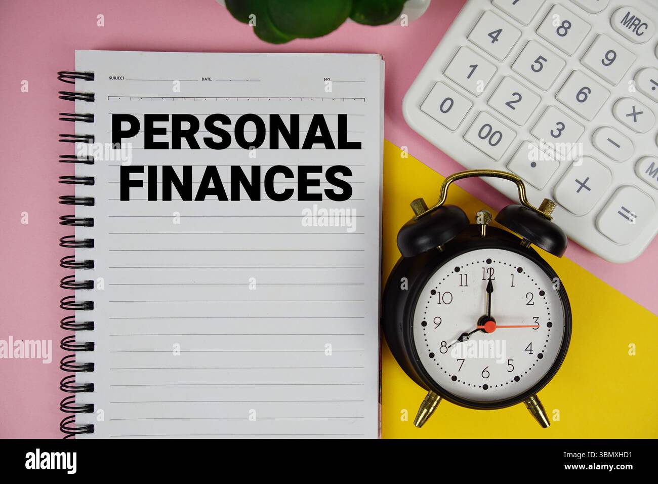 Text für persönliche Finanzen auf Notizblock mit Taschenrechner und Wecker auf rosafarbenem Hintergrund Stockfoto