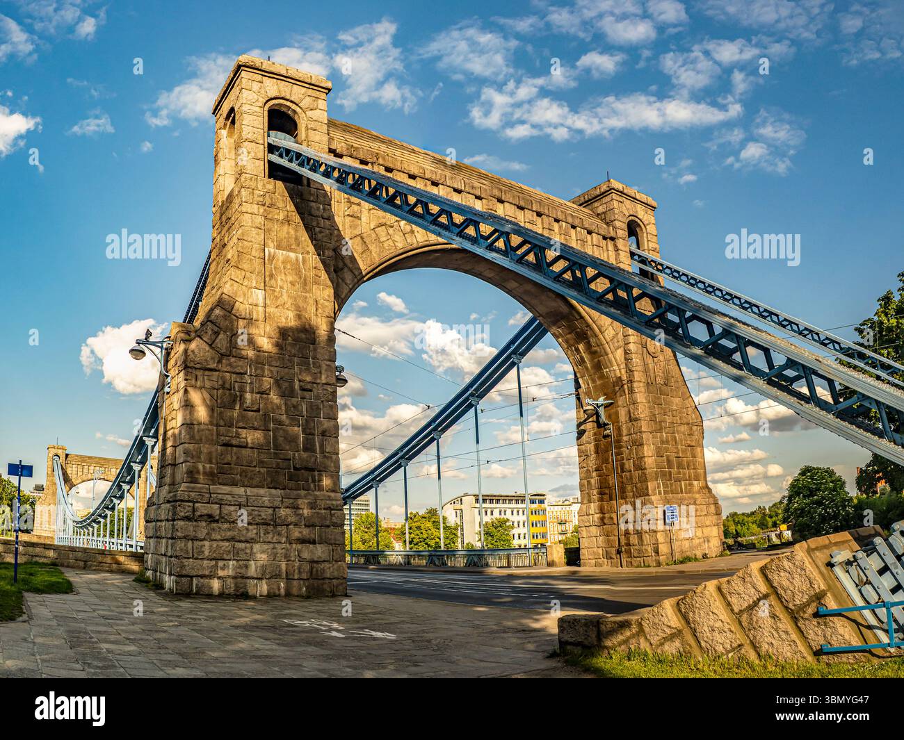 Eine große Hängebrücke mit historischer Architektur erstreckt sich anmutig unter einem hellblauen Himmel Stockfoto