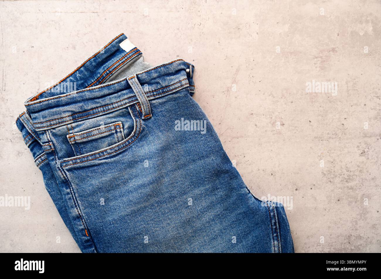 Klassische, gefaltete Jeans in Blau auf dem Schreibtisch mit Platz für Ideen als Flat-Lay Stockfoto