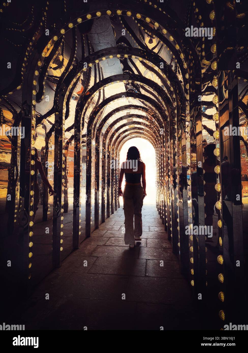 Frau, die den beleuchteten und spiegelnden Tunnel im Londoner Theaterviertel hinuntergeht. Die neue Infinity Chamber von Covent Garden befindet sich in Conduit Court Stockfoto