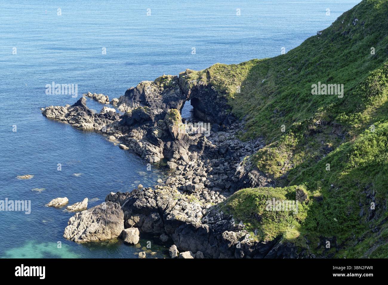 Felsige Küste und Felsentor an der Südostküste nahe der Südspitze von Cornwall am Ärmelkanal. Cadgwith, Cornwall, Südwestengland, Gr Stockfoto