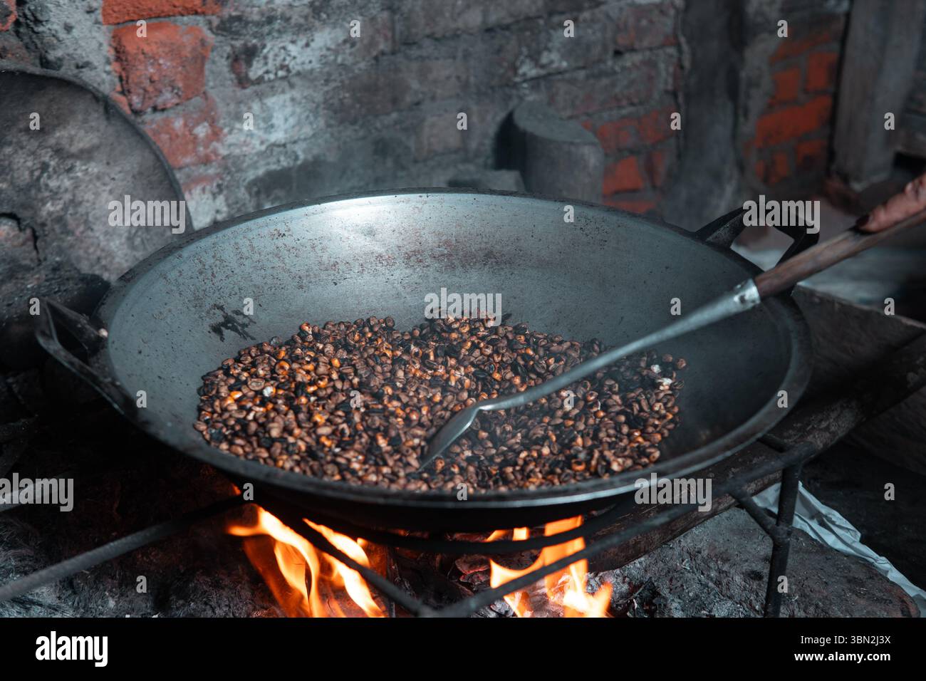 Traditionelles Rösten von Kaffeebohnen gemischt mit Mais über einem Brennholzofen. Eine lokale Technik, um einen einzigartigen Geschmack zu kreieren, in einem rustikalen Dorf festgehalten. Stockfoto