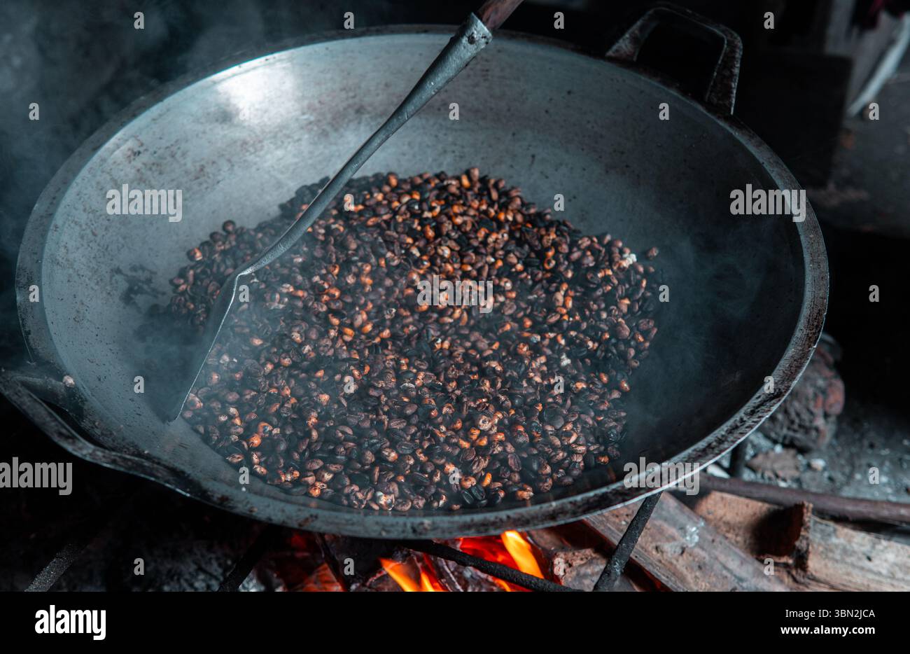 Traditionelles Rösten von Kaffeebohnen gemischt mit Mais über einem Brennholzofen. Eine lokale Technik, um einen einzigartigen Geschmack zu kreieren, in einem rustikalen Dorf festgehalten. Stockfoto