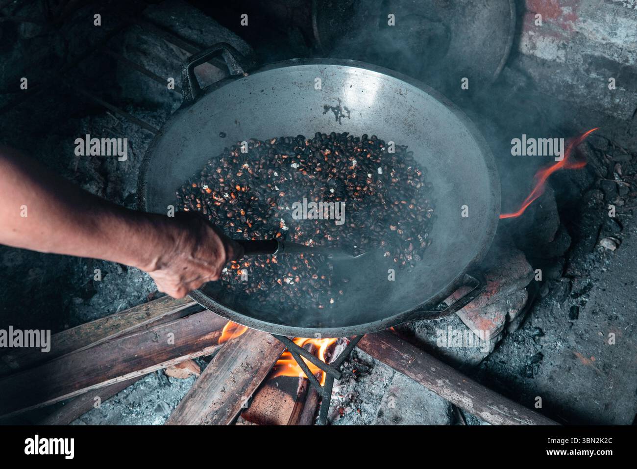 Traditionelles Rösten von Kaffeebohnen gemischt mit Mais über einem Brennholzofen. Eine lokale Technik, um einen einzigartigen Geschmack zu kreieren, in einem rustikalen Dorf festgehalten. Stockfoto