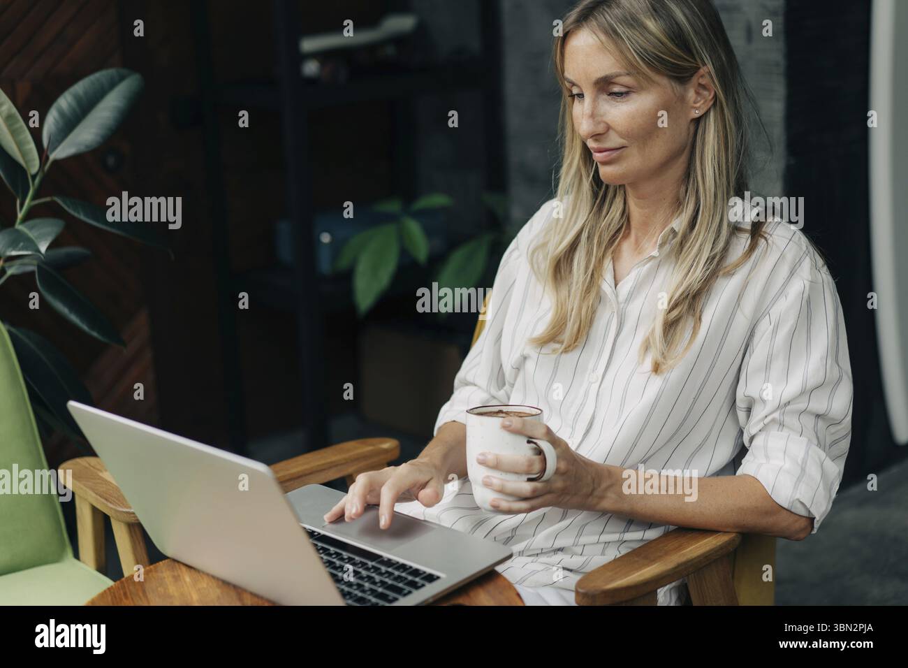 Eine Frau sitzt in einem Café und arbeitet an einem Laptop Stockfoto