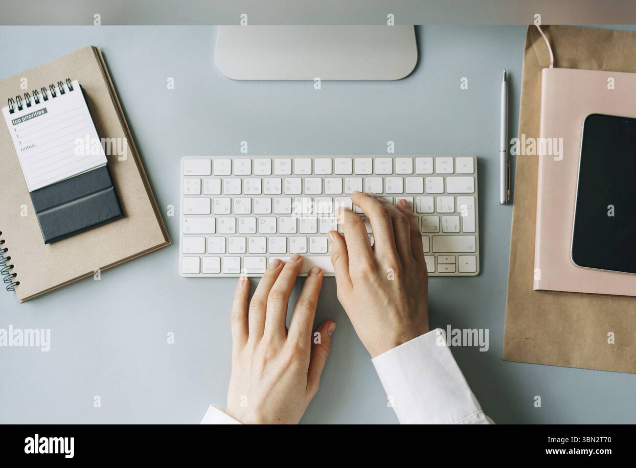 Elegante weibliche Hände, die auf einer Computertastatur tippen, Ansicht von oben auf einen modernen Arbeitsplatz Stockfoto