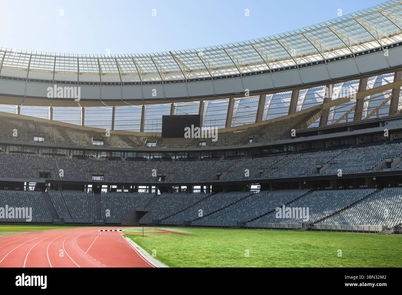 Das Athletics Stadion zeigt eine flache rote Laufbahn, einen grünen Rasen, eine Anzeigetafel und Stahlträger Stockfoto