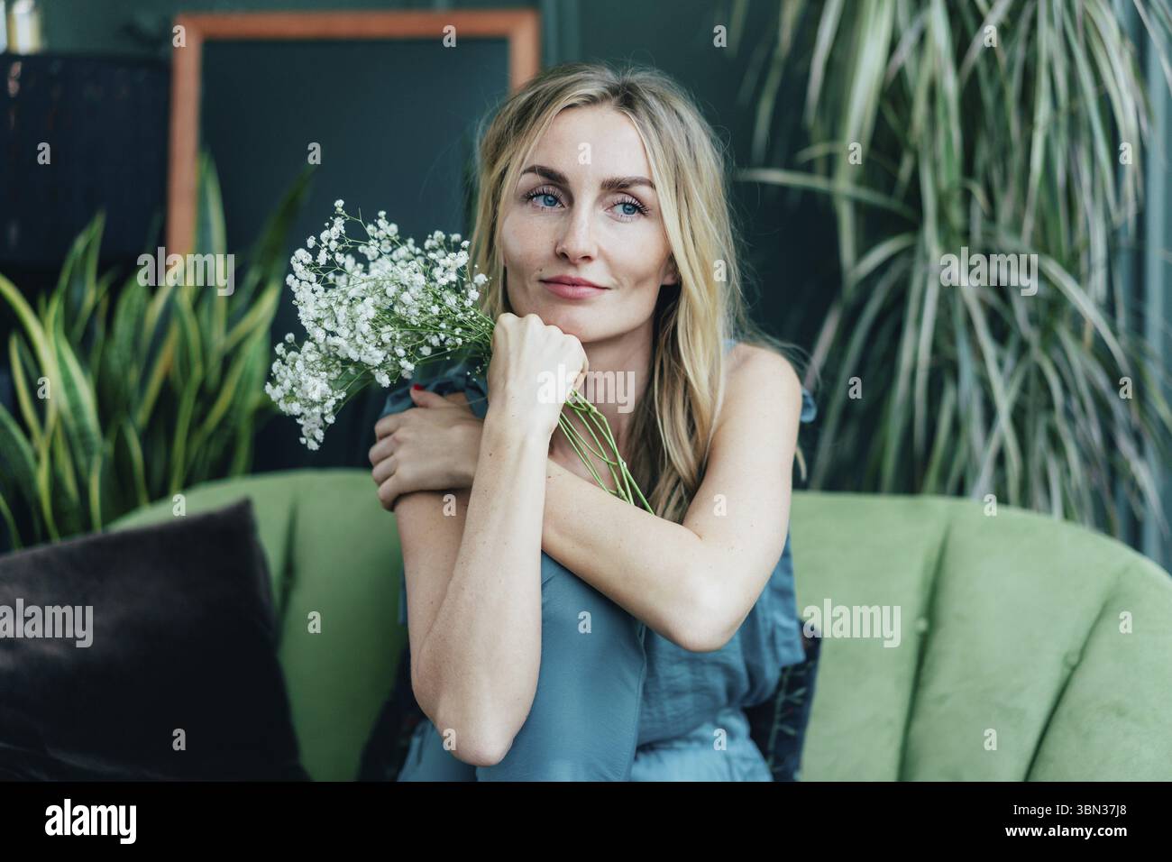 Portraet einer blonden Frau in einem gruenen Interieur. Fruehlingsfrisches Konzept. Natürliche Schönheit Stockfoto