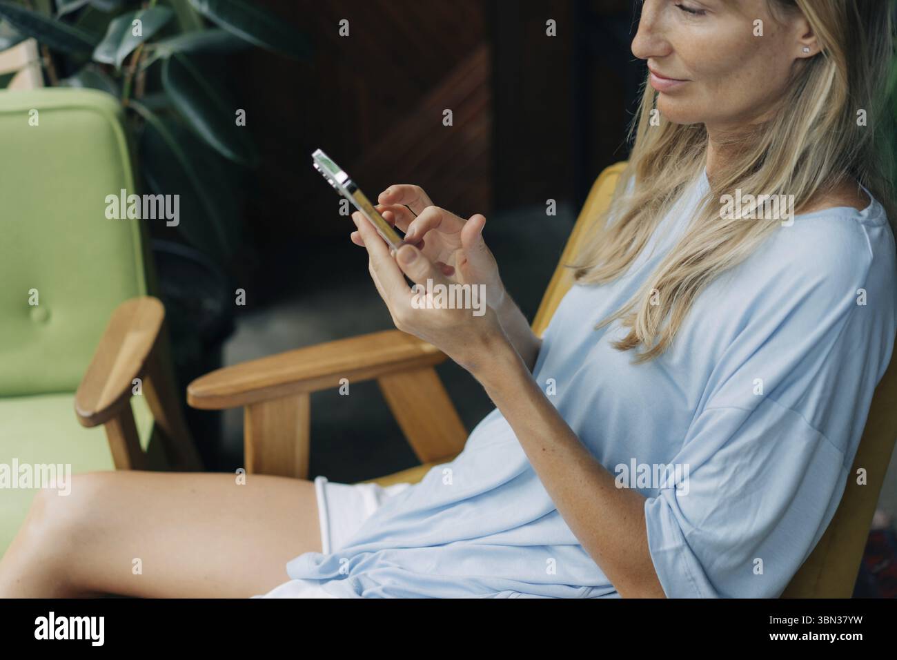 Eine Frau sitzt in einem Cafe und benutzt ein Mobiltelefon, um in sozialen Netzwerken zu surfen Stockfoto
