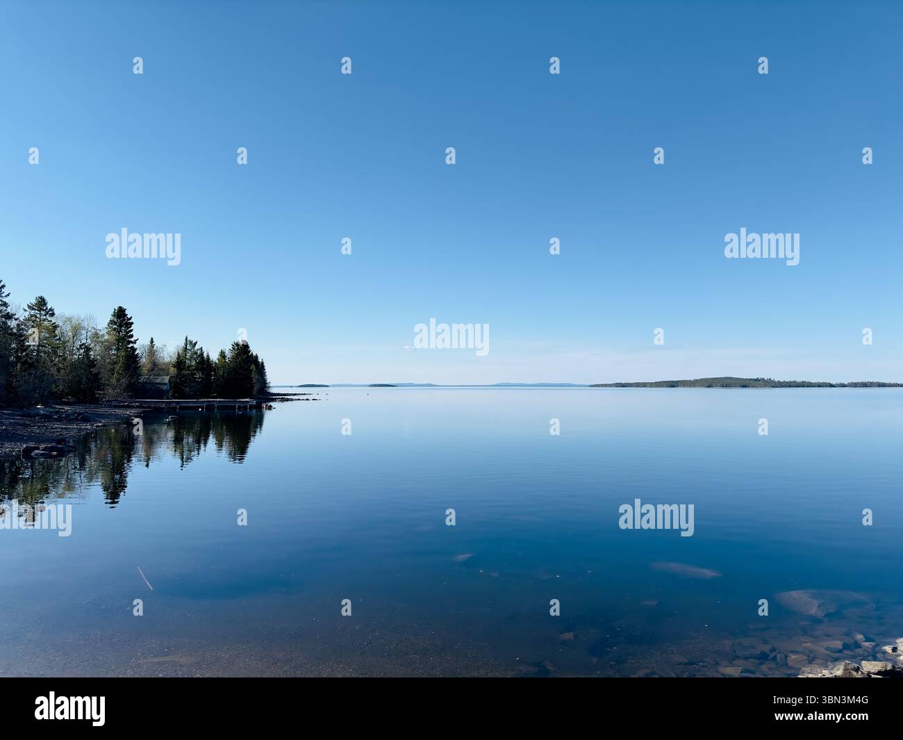 Der hellblaue Himmel trifft auf das ruhige Wasser eines riesigen Sees an einem sonnigen Tag, nördlich von Schweden Stockfoto