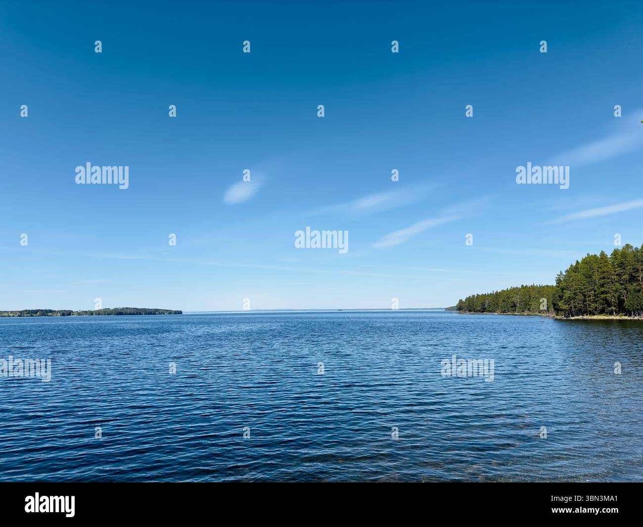 Der hellblaue Himmel trifft auf das ruhige Wasser eines riesigen Sees an einem sonnigen Tag, nördlich von Schweden Stockfoto