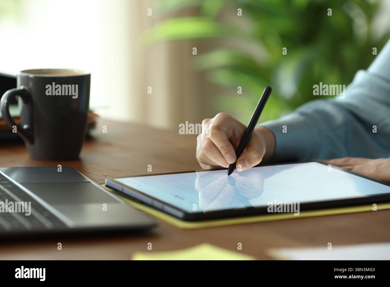 Nahaufnahme des Porträts der Hände des Büroarbeiters mit dem Eingabestift, um auf einem Holztisch handschriftlich auf ein Tablet zu schreiben Stockfoto