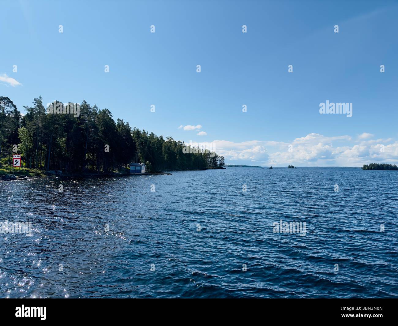 Der hellblaue Himmel trifft auf das ruhige Wasser eines riesigen Sees an einem sonnigen Tag, nördlich von Schweden Stockfoto