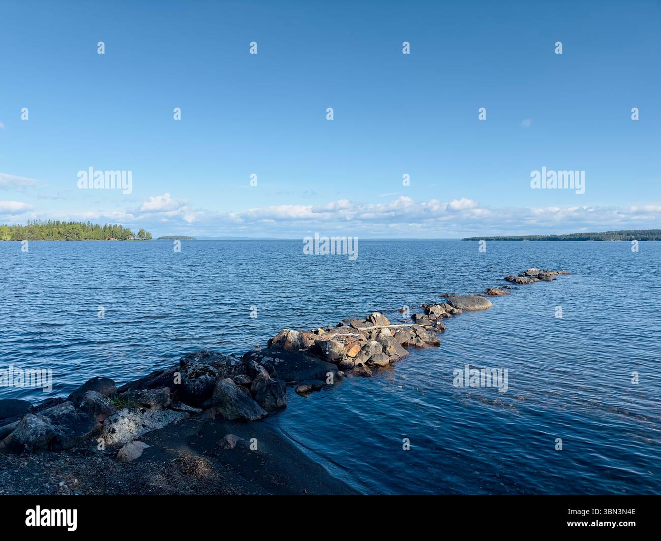Der hellblaue Himmel trifft auf das ruhige Wasser eines riesigen Sees an einem sonnigen Tag, nördlich von Schweden Stockfoto