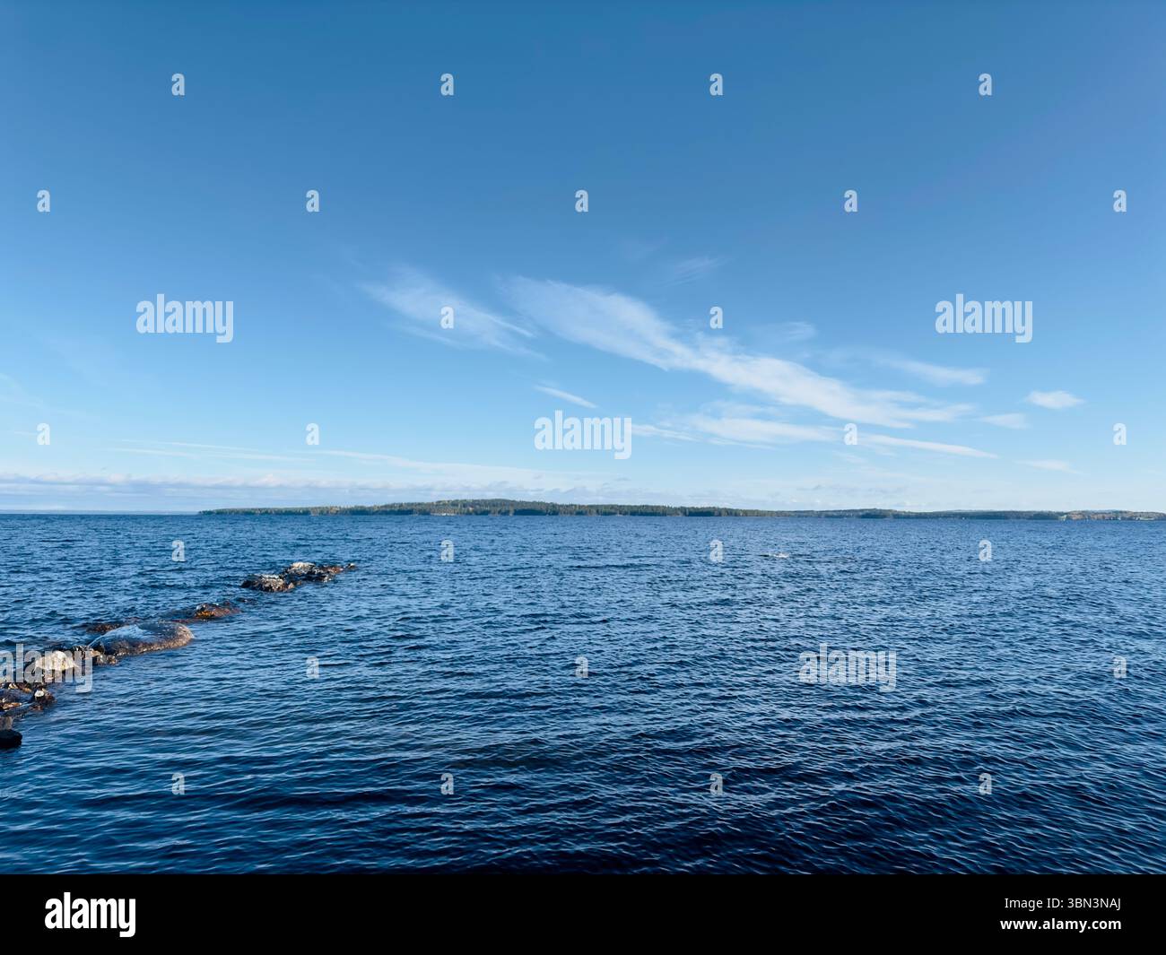 Der hellblaue Himmel trifft auf das ruhige Wasser eines riesigen Sees an einem sonnigen Tag, nördlich von Schweden Stockfoto