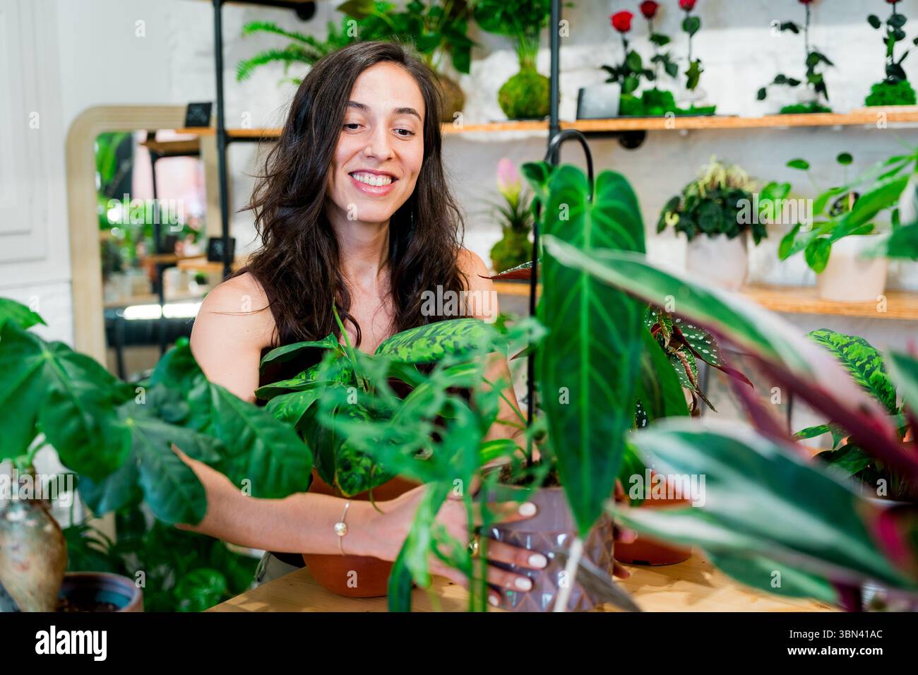 Floristin steht im Blumenladen, tausendjährige Kleinunternehmer-Eigentümerin mit ihren Pflanzen und Blumen Stockfoto