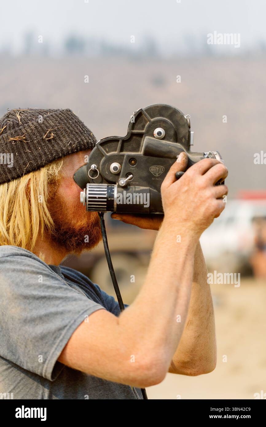 Kameramann filmt mit Super 8-Filmkamera in Wüstenlandschaft Stockfoto