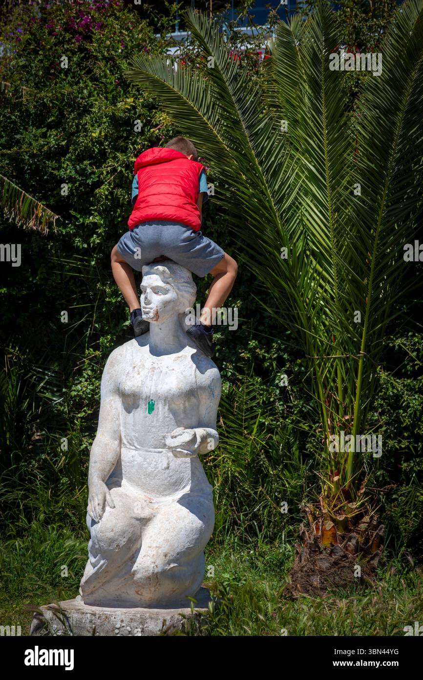 Kind spielt auf einer Statue in schlechtem Zustand Stockfoto