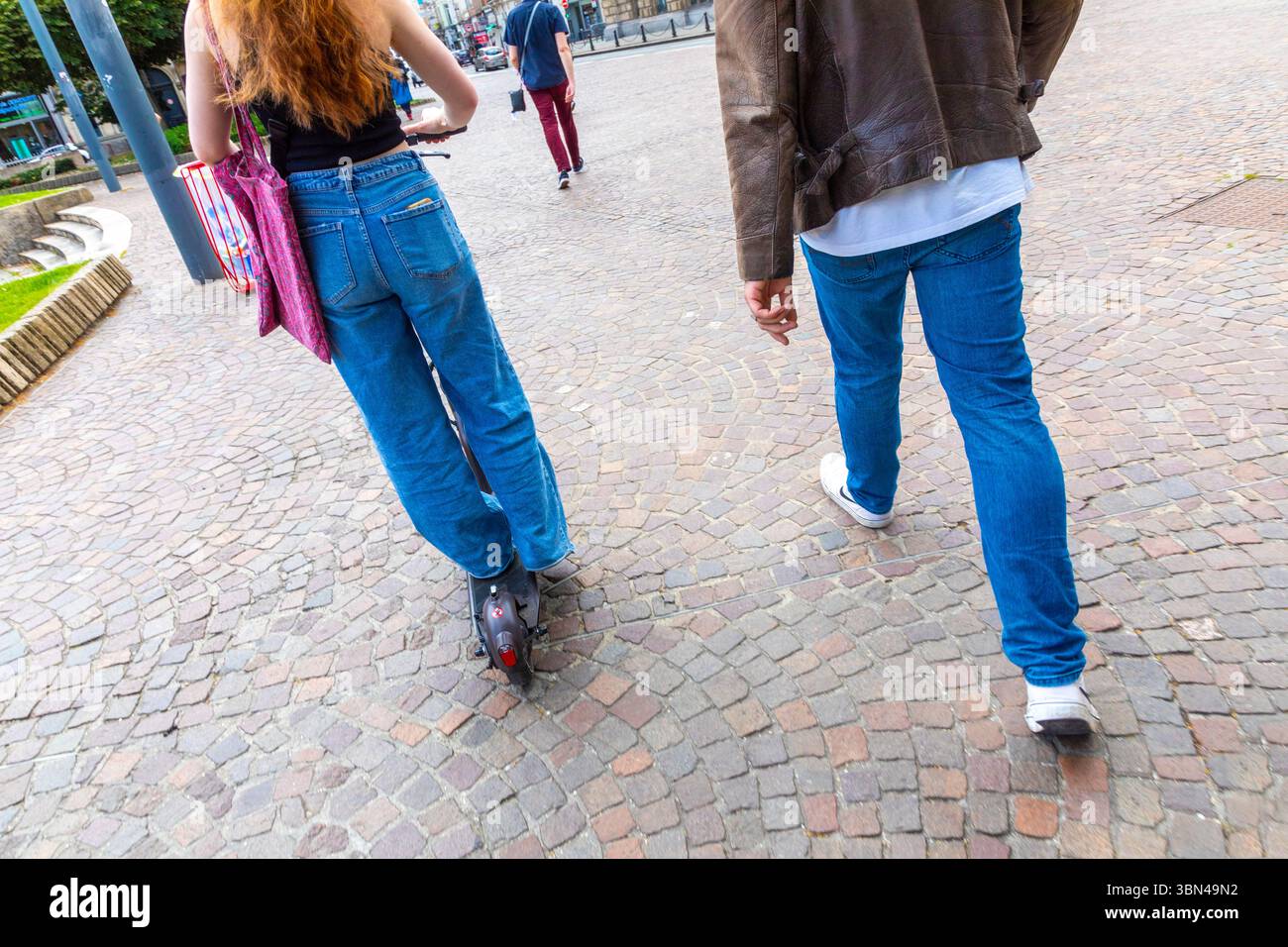 Ein Paar auf der Straße. Er zu Fuß, sie auf dem Roller. Stockfoto