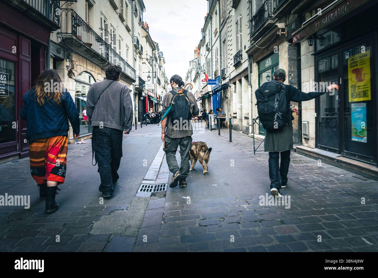 Gruppe junger Obdachloser, die in einer Fußgängerzone mit einem Hund laufen. Oft Dog Punk genannt. Stockfoto