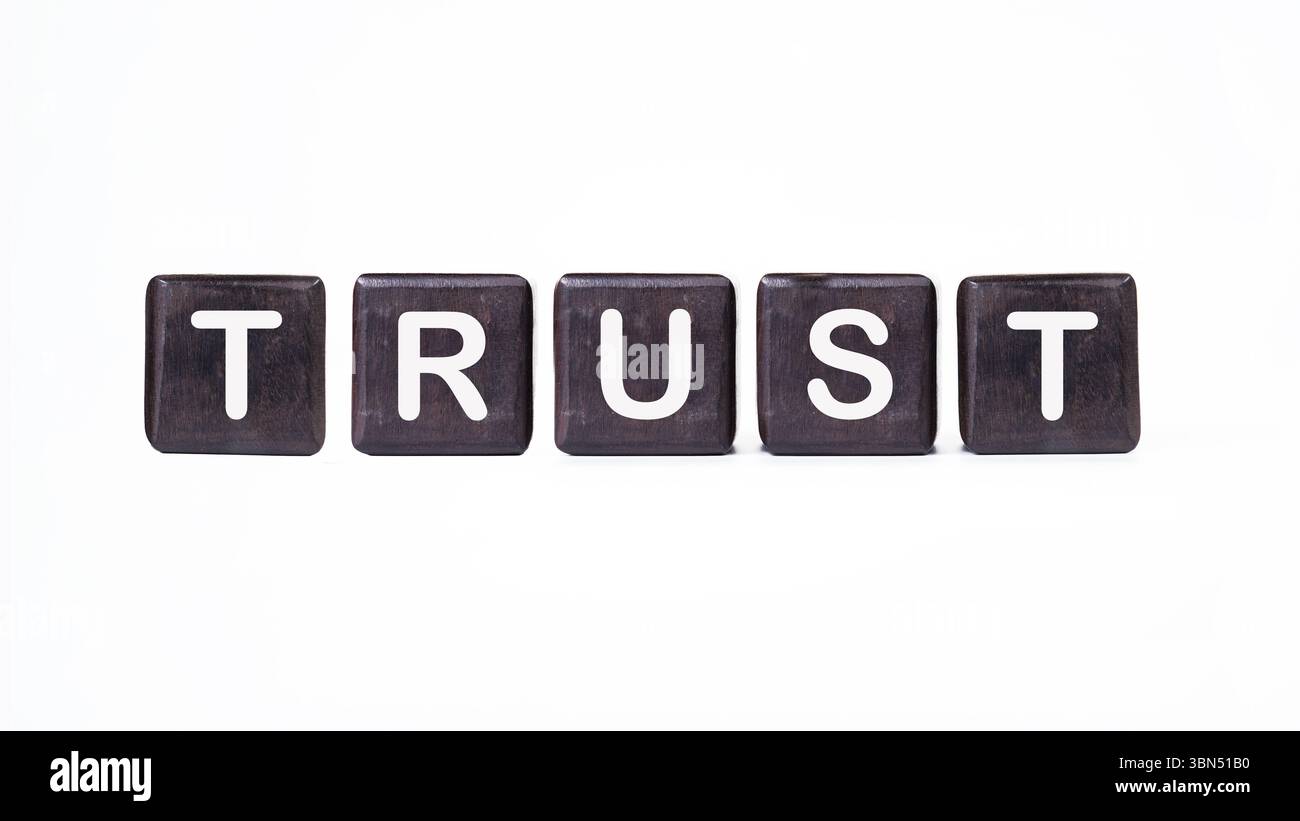 Das Konzeptwort TRUST ist aus Holzwürfeln zusammengesetzt. Investitionen auf der Grundlage eines Vertrauenskonzepts. Stockfoto