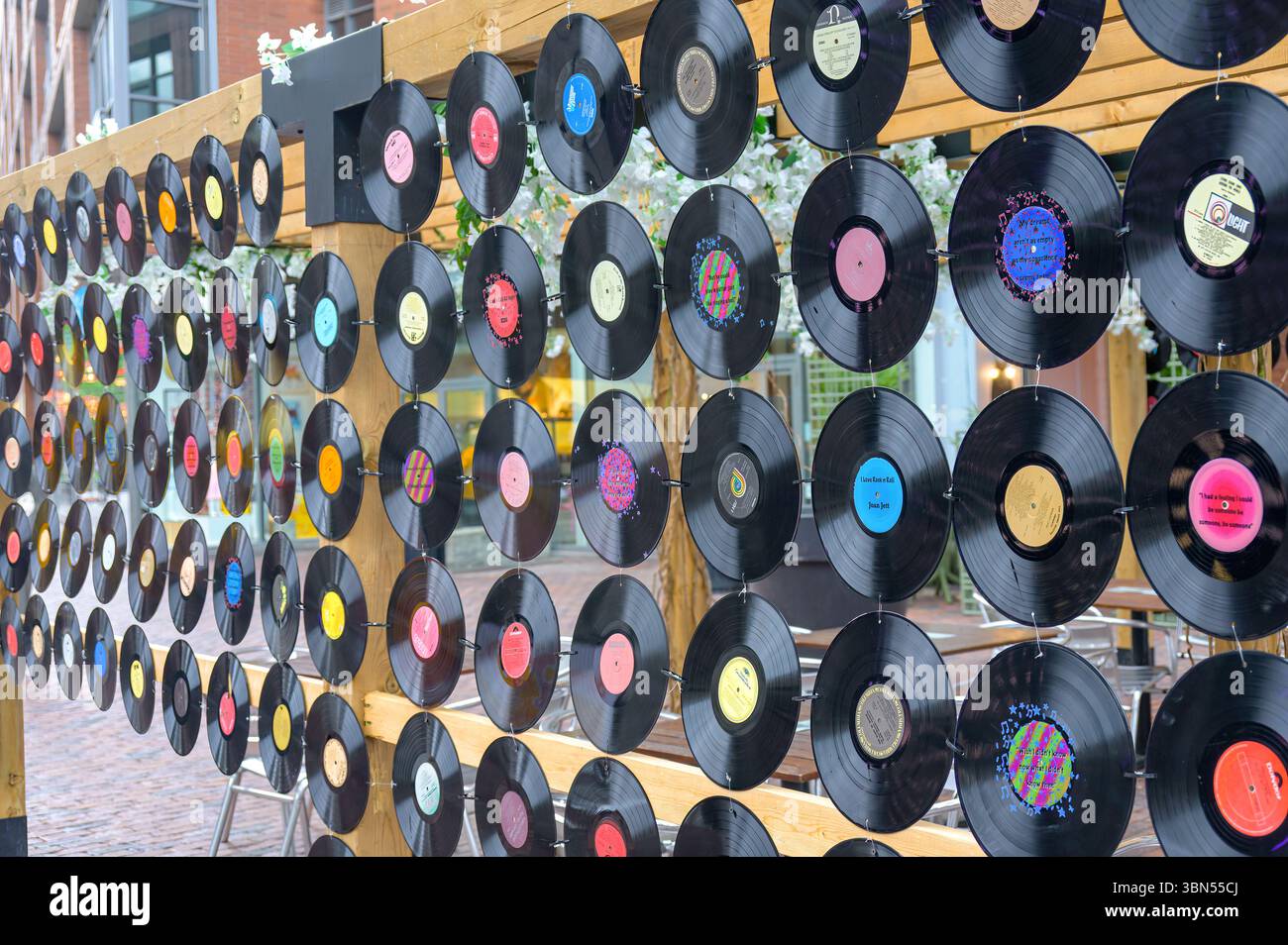 Eine Nahaufnahme einer dekorativen Wand im Distillery District zeigt Dutzende von bunten Schallplatten, die an Holzbalken befestigt sind und ein kreatives Outd bilden Stockfoto