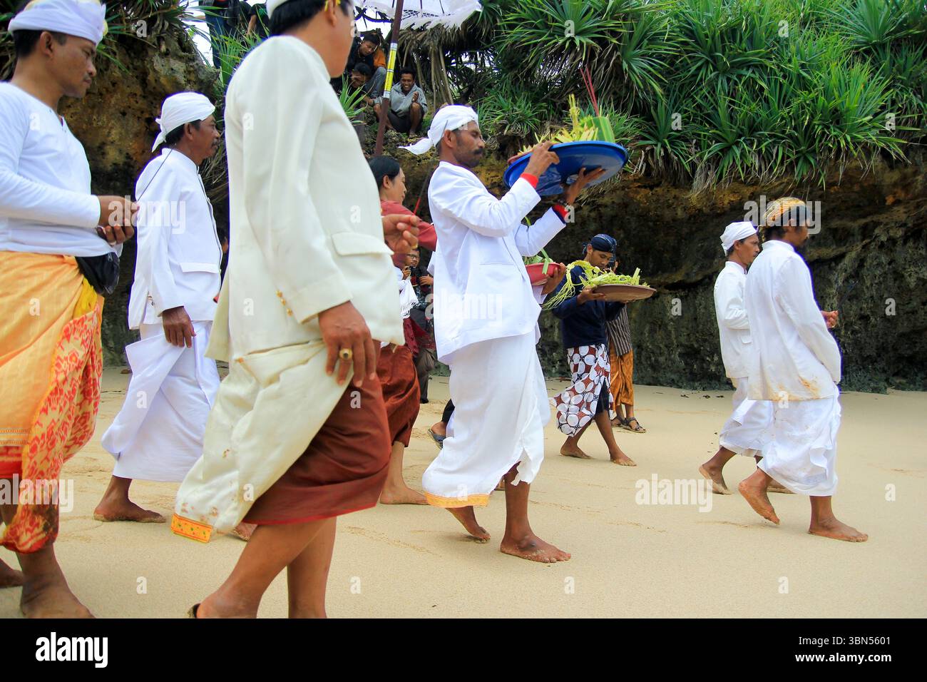 Hinduistische Anhänger bringen Opfer an den Strand, die während der Melasti-Zeremonie ins Meer geschwemmt werden. Stockfoto