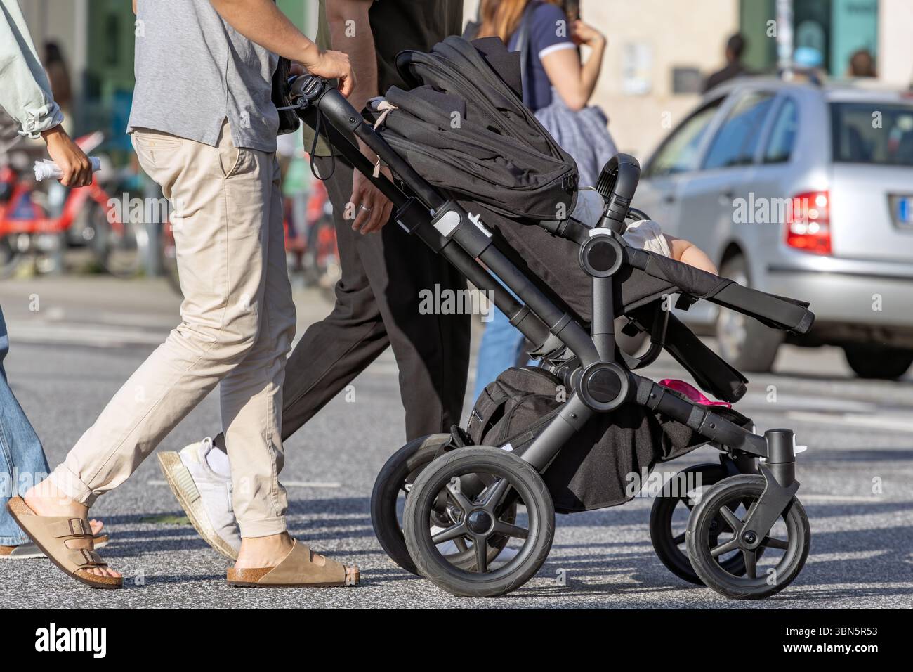 Vater in Sandalen, der den Kinderwagen schiebt Stockfoto