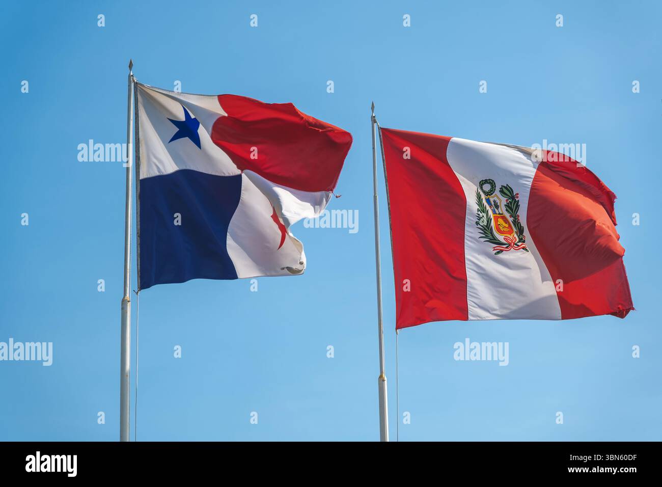 Nationalflaggen von panama und peru winken an einem sonnigen Tag auf Fahnenmasten im Wind Stockfoto