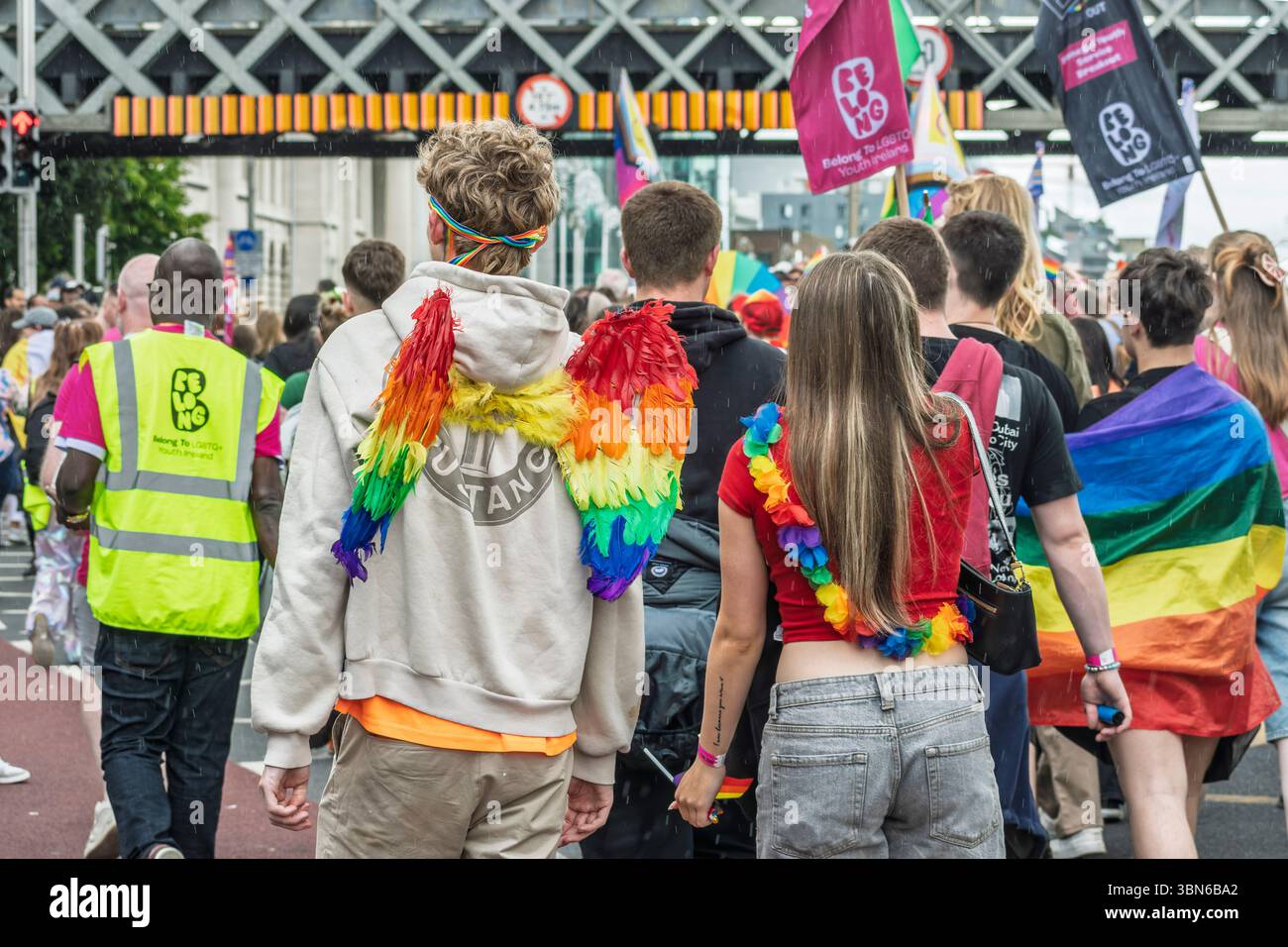 Ein junges Paar in Engelsflügeln und Regenbogenaccessoires spaziert mit Freude durch die Dublin Pride Parade. 28. Juni 2025 Stockfoto