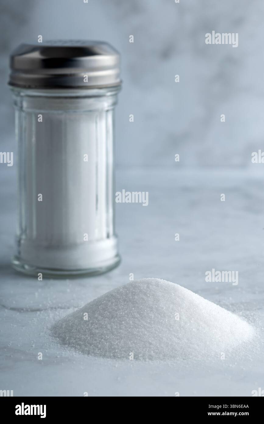Makelloser Salzstreuer mit feinem weißem Salz auf eleganter Marmoroberfläche. Stockfoto