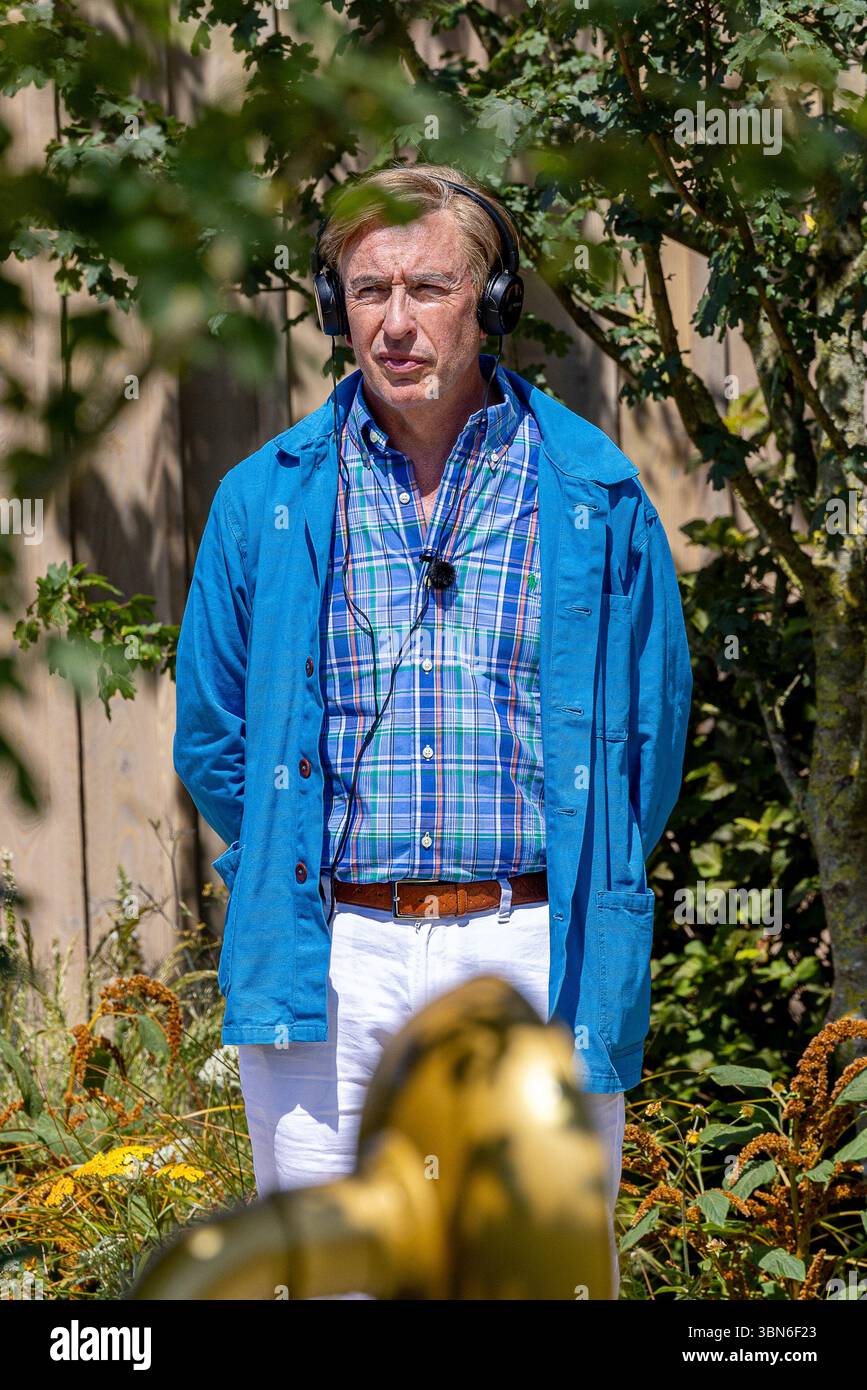 Steve Coogan wurde beim Hampton Court Palace Garden Festival als Alan Partridge als Schauspieler gesehen. Er trat im Alan Partridge Sound Bath Garden auf, entworfen von Joe und Laura Carey, während er bei 32 °C mit einem Handventilator und einem Regenschirm kühl blieb. Quelle: David Betteridge/Alamy Live News Stockfoto