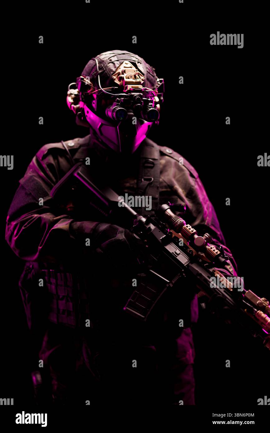 Bewaffneter taktischer Soldat, der Spezialausrüstung unter intensiver Beleuchtung trägt und Geheimhaltung und Strategie miteinander verbindet. Stockfoto
