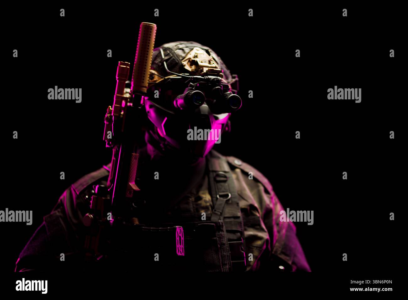 Ein taktischer Soldat, ausgestattet mit Nachtsichtbrille und Waffen, beleuchtet mit lebendigem Licht. Zeigt Kriegsführung, Technologie und Bereitschaft. Stockfoto