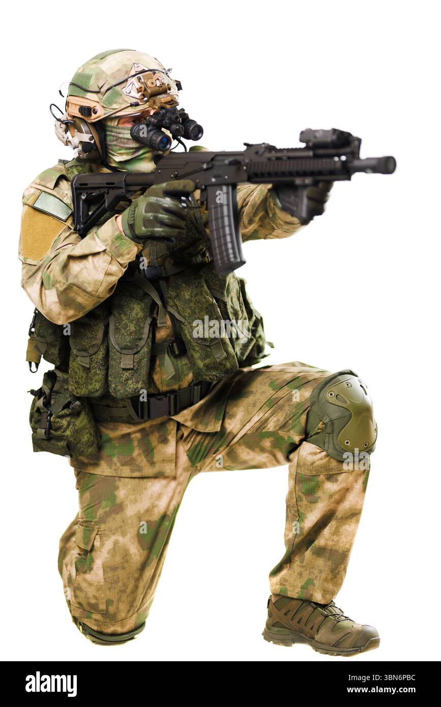 Ein bewaffneter Soldat, der mit moderner taktischer Ausrüstung ausgestattet ist, kniet und zielt, zeigt Präzision und Bereitschaft, gekleidet in grüner Tarnung. Die Abbildung Re Stockfoto