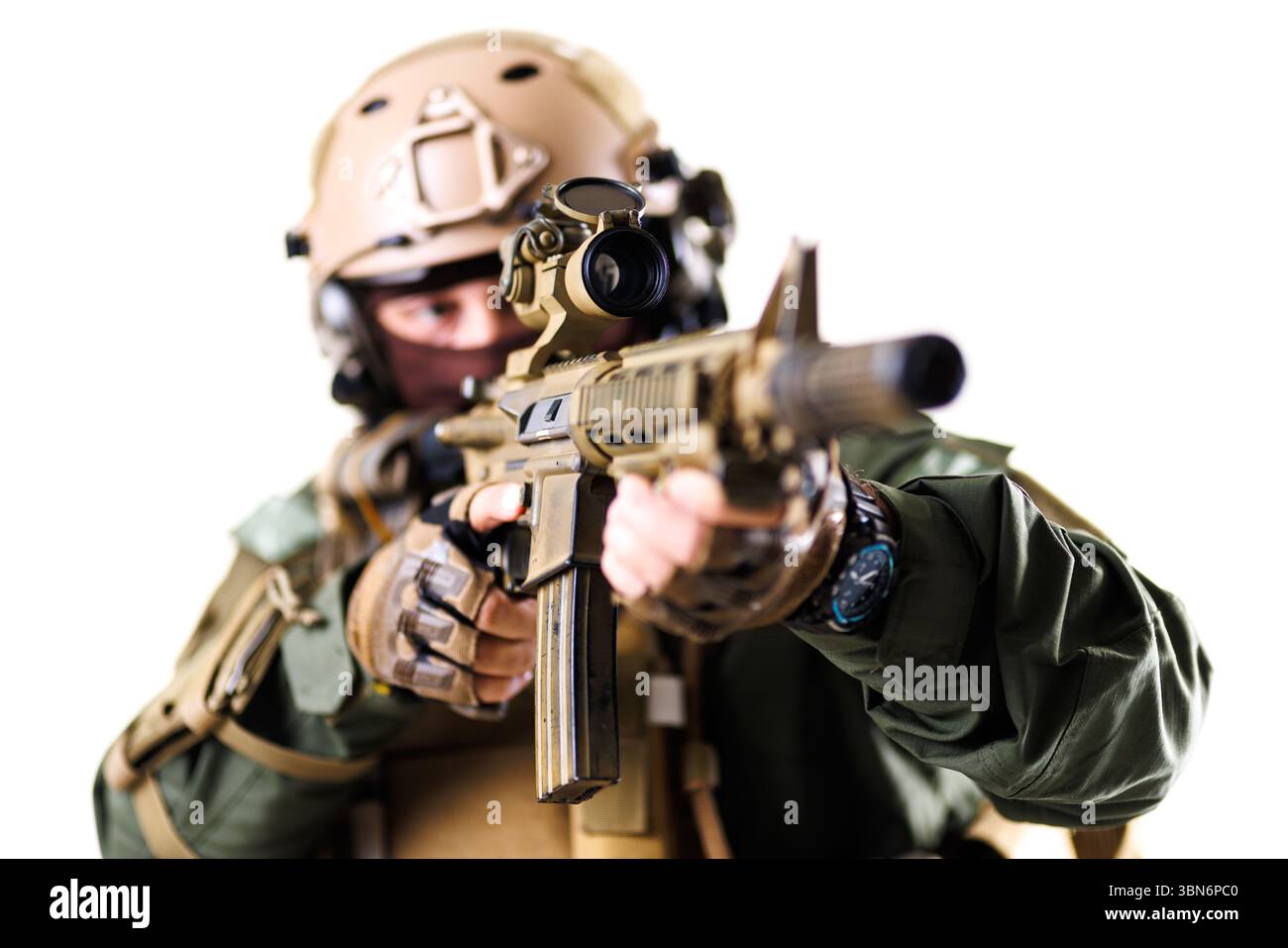 Ein taktischer Soldat in fortgeschrittener Militärkleidung, der ein Gewehr mit Fokus zielt. Der verschwommene Hintergrund verstärkt die Handlung und Disziplin, die darin vermittelt werden Stockfoto