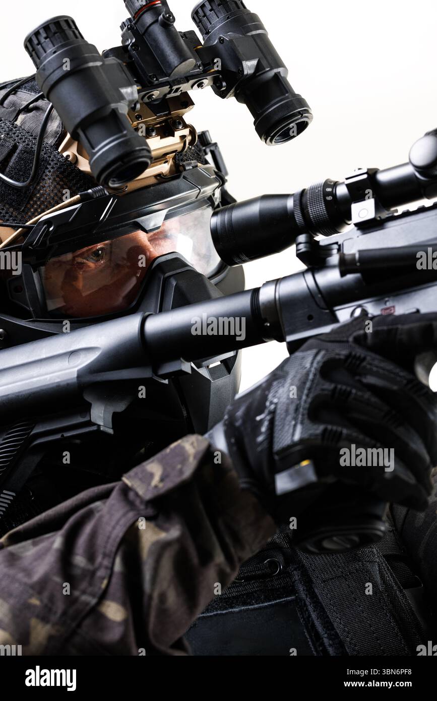 Nahaufnahme eines Soldaten in fortschrittlicher taktischer Ausrüstung, einschließlich Gewehr, Nachtsichtbrille und Schutzhelm, was beispielhaft für Bereitschaft und Präzision ist Stockfoto