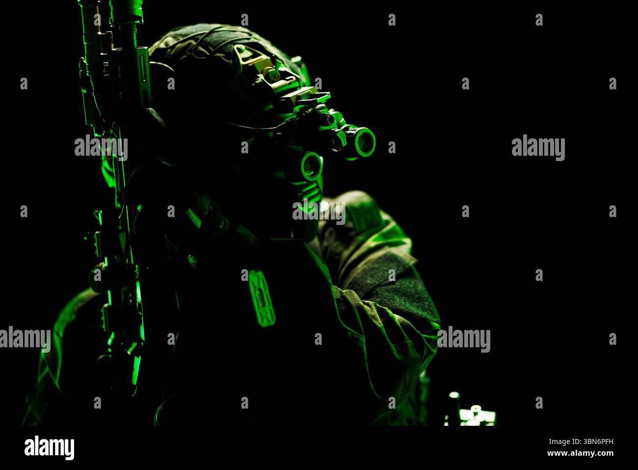 Ein schwer bewaffneter Fahrer, der mit Nachtsichttechnologie in einer auffälligen grünen Silhouette ausgestattet ist und als Symbol für taktische Bereitschaft und moderne Mili erfasst wird Stockfoto
