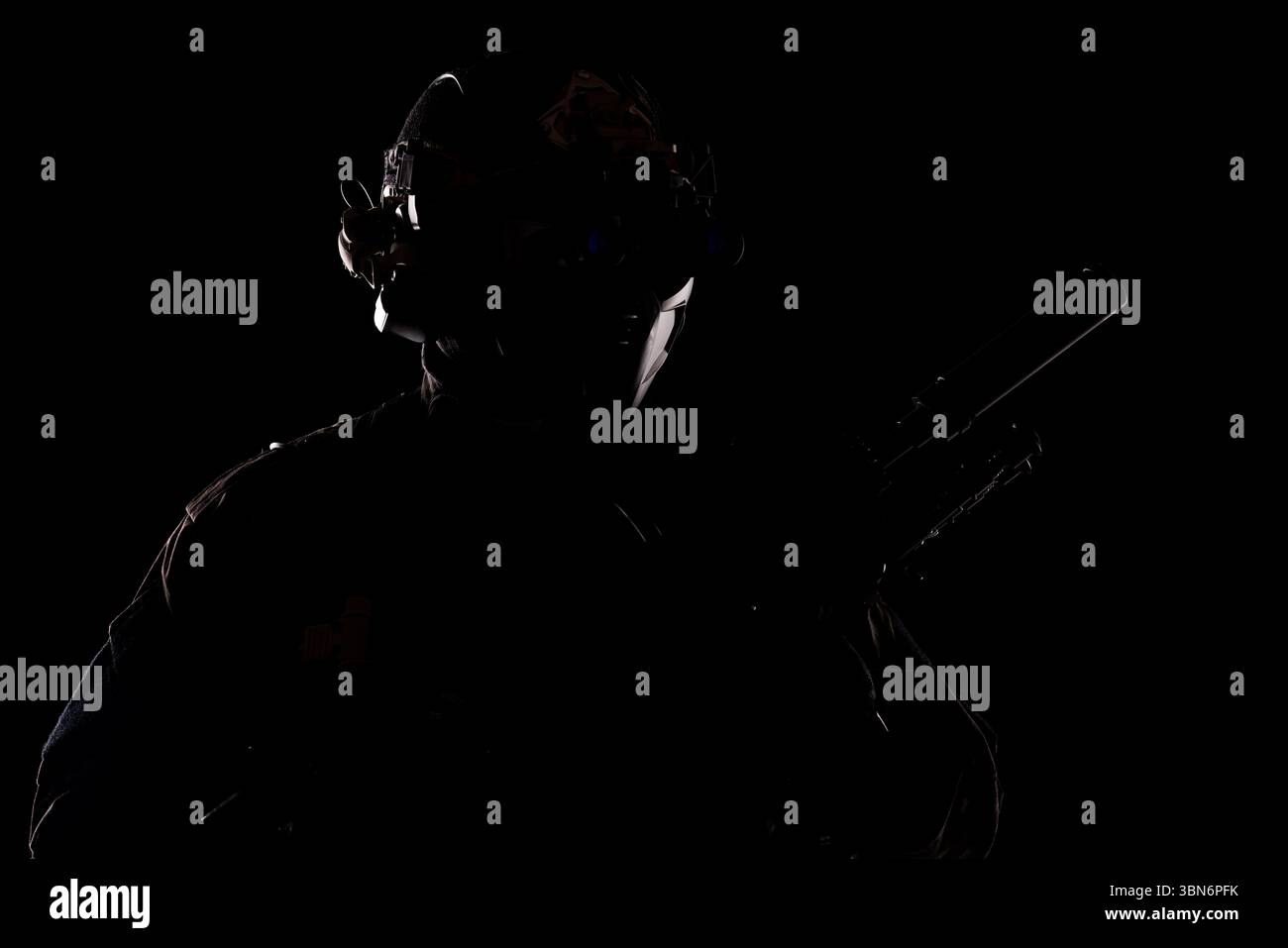 Eine dramatische Silhouette, die eine taktische Figur mit Nachtsichtbrille und fortschrittlicher Ausrüstung zeigt und Themen wie Geheimhaltung und Präzision hervorhebt Stockfoto