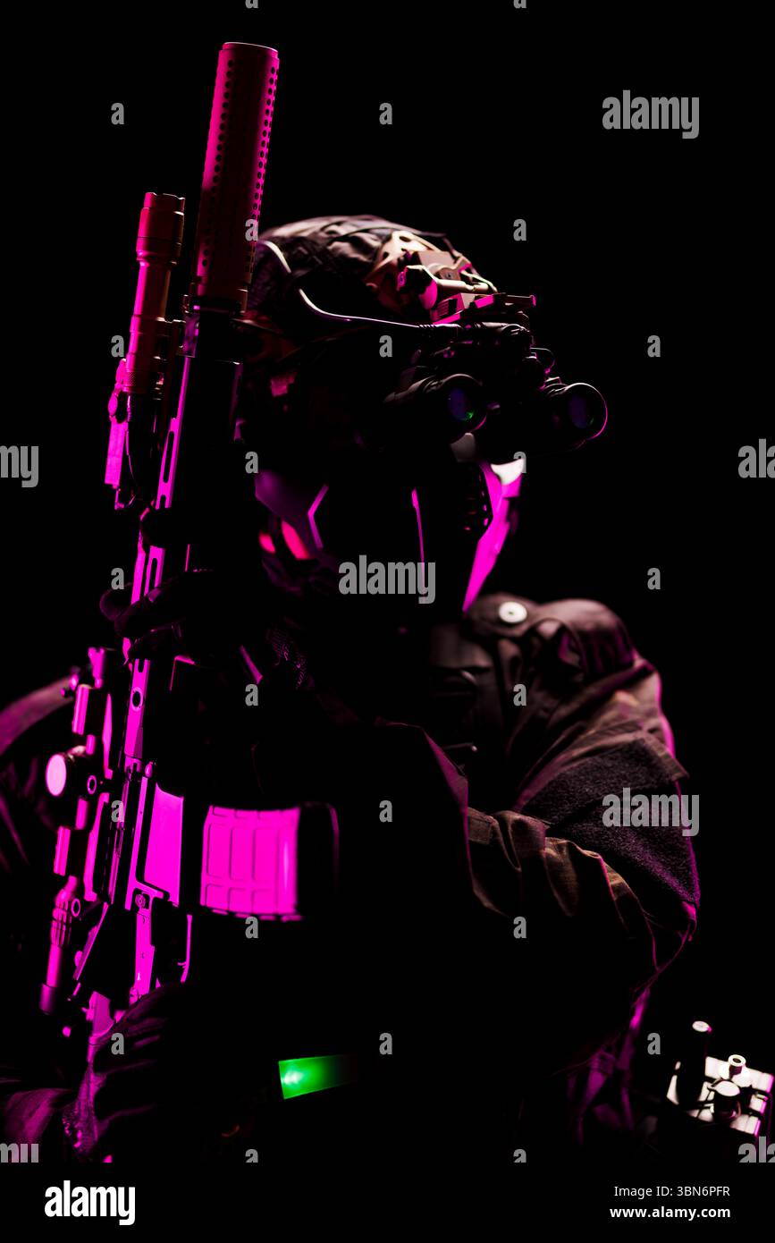 Silhouettenansicht eines taktischen Soldaten, der mit fortschrittlicher Militärausrüstung und Waffen ausgestattet ist, unter dramatischer rosa und grüner Beleuchtung, die einen starken Sinn schafft Stockfoto