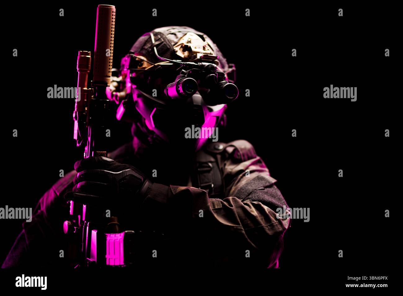 Ein taktischer Fahrer, der mit fortschrittlicher Nachtsichtausrüstung und Schutzkleidung unter dramatischer rosa Beleuchtung ausgestattet ist. Stockfoto