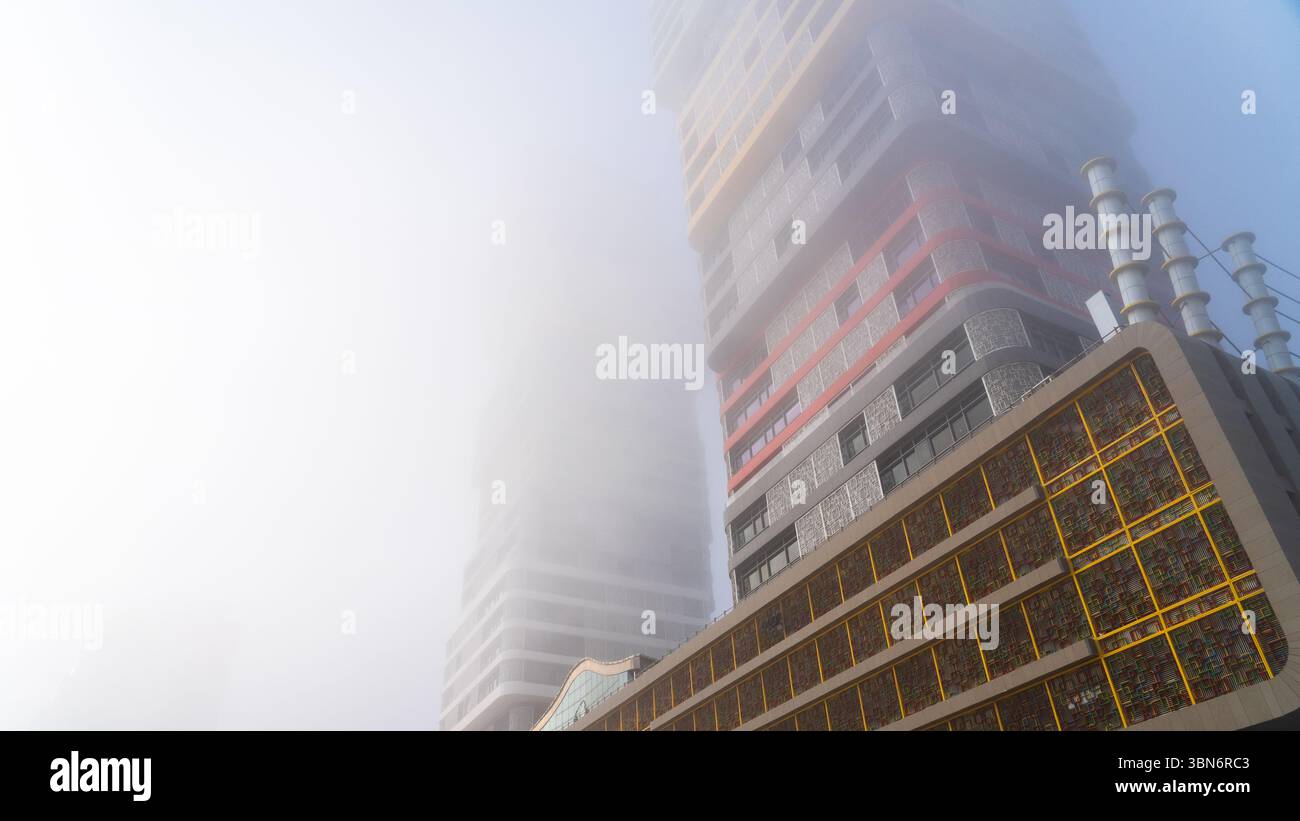 Doha, Katar – 24. Februar 2025: Ein nebeliger Morgen in Doha mit Wolkenkratzern, die teilweise im Nebel verborgen sind und eine geheimnisvolle und ruhige Stadtlandschaft schaffen. Stockfoto