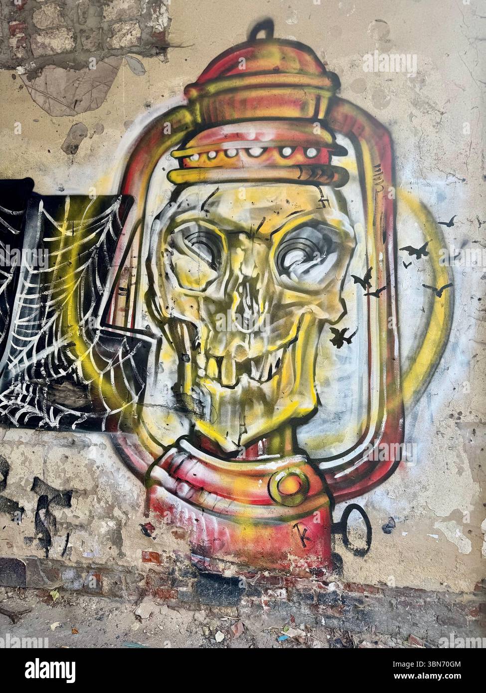 Graffiti-Straßenkunst eines Schädels in einer altmodischen Laterne an einer verwitterten Wand in Gent, Belgien. - Smartphone-aufgenommenes Stockfoto