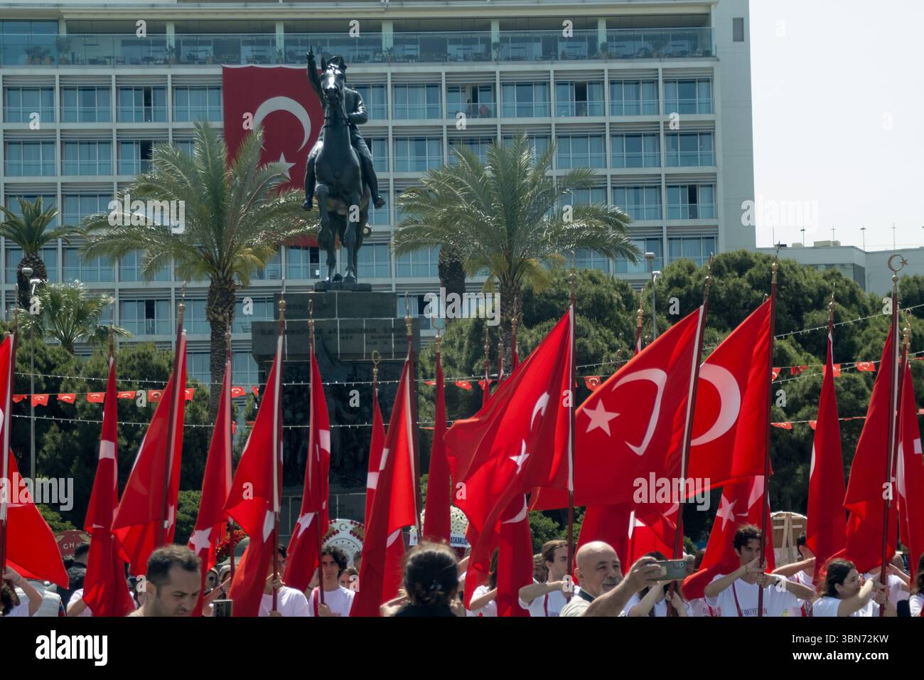Izmir, Türkei - 19. Mai 2025: Menschenmassen wehen während der Jugend- und Sportfeierlichkeiten zum Gedenken an Atatürks Gedenken auf dem Stadtplatz riesige türkische Fahnen Stockfoto