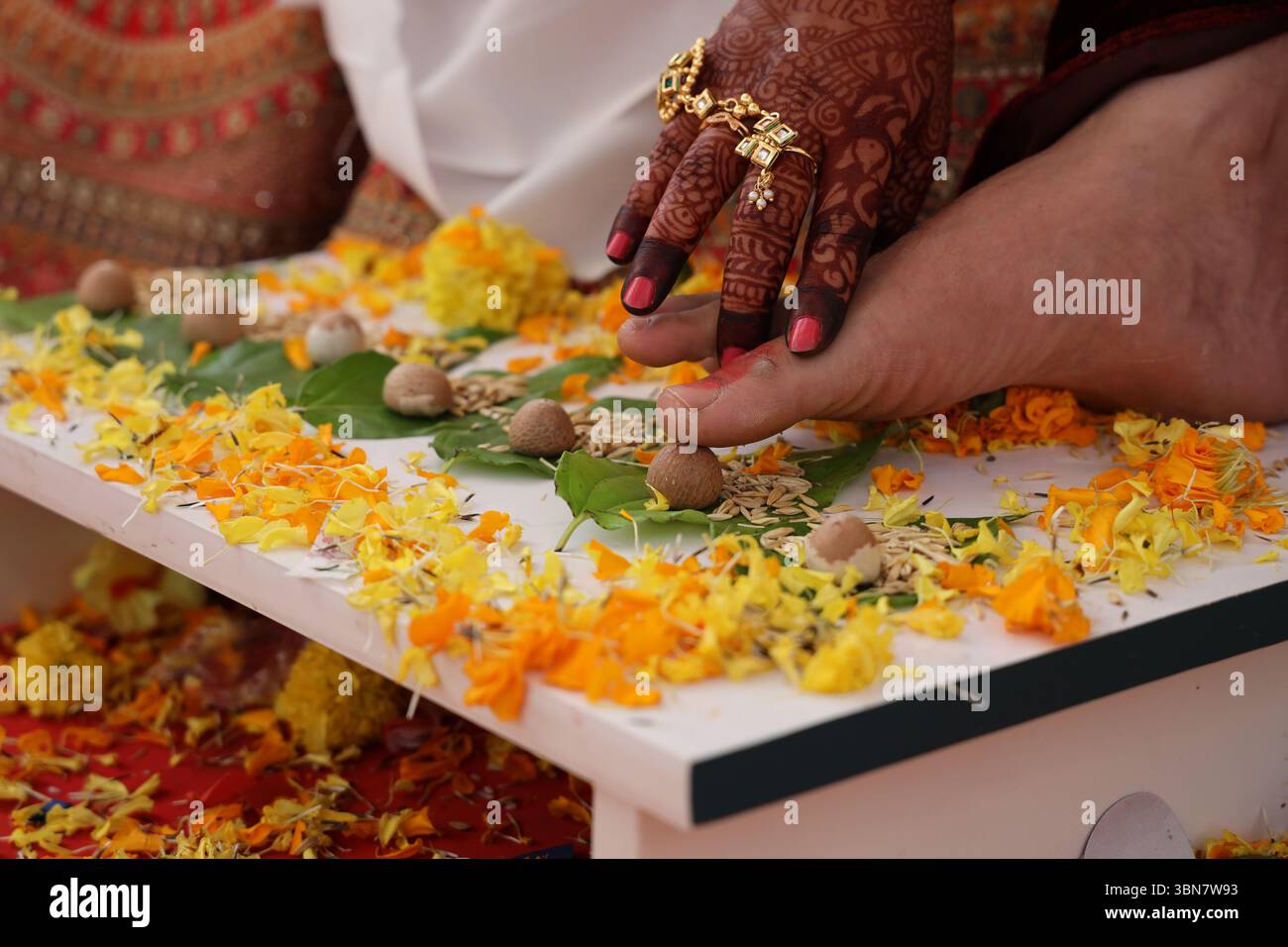 Ein traditionelles indisches Hochzeitsritual, speziell ein Moment aus dem „Saptpadi“ oder „Mangal Phera“. Braut, die ihren Fuß auf den Fuß des Bräutigams setzt Stockfoto