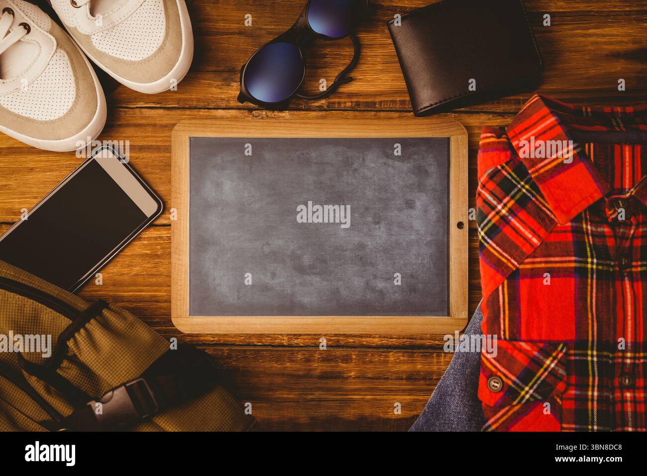 Leere hölzerne Tafel wird in flachem Design mit wichtigen Reiseutensilien und Kopierraum gezeigt Stockfoto